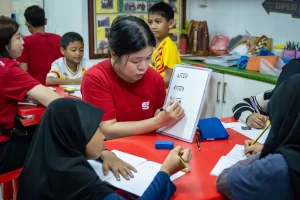 A woman volunteer in Malaysia teaching a group of children mathematics.