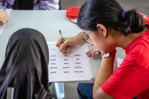 seorang guru perempuan mengajar anak murid dalam aktiviti sukarelawan.