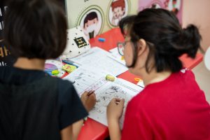 seorang sukarelawan perempuan mengajar seorang kanak-kanak perempuan.