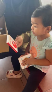 A small boy holding a book with his mom who is also holding a red book to underscore the importance of what is early childhood education.