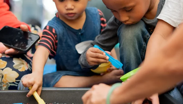 Two little boys playing in a sandbox as an example of what is early childhood education.