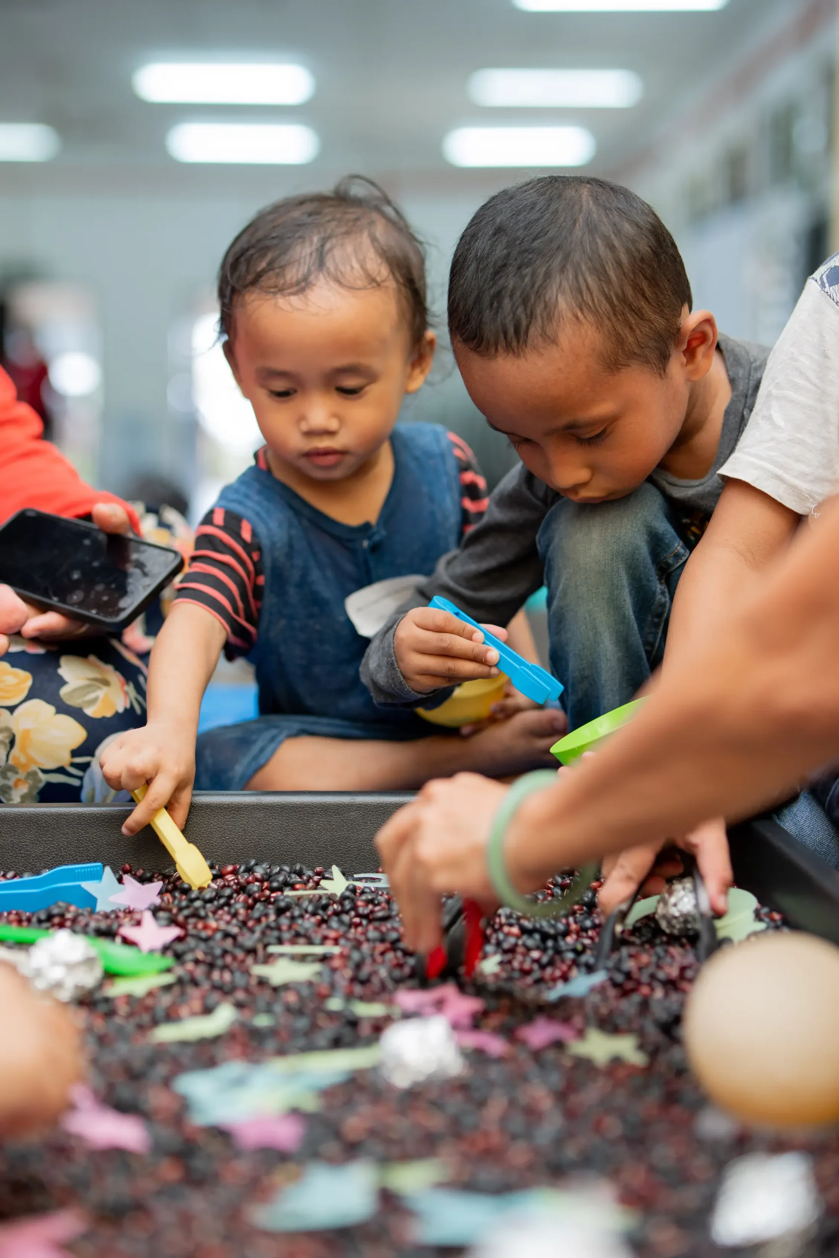 Two little boys playing in a sandbox as an example of what is early childhood education.